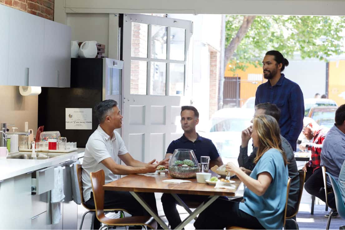 colleagues eating lunch in kitchen by door