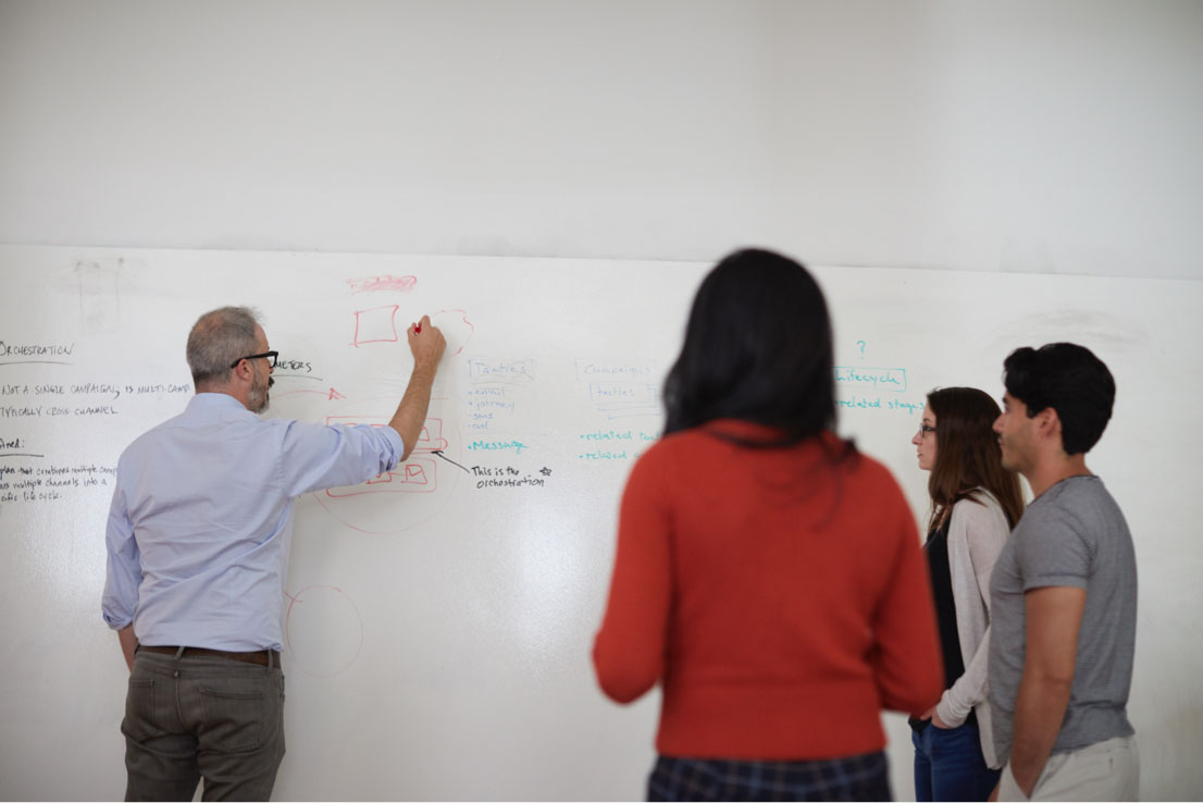 older man drawing on whiteboard 